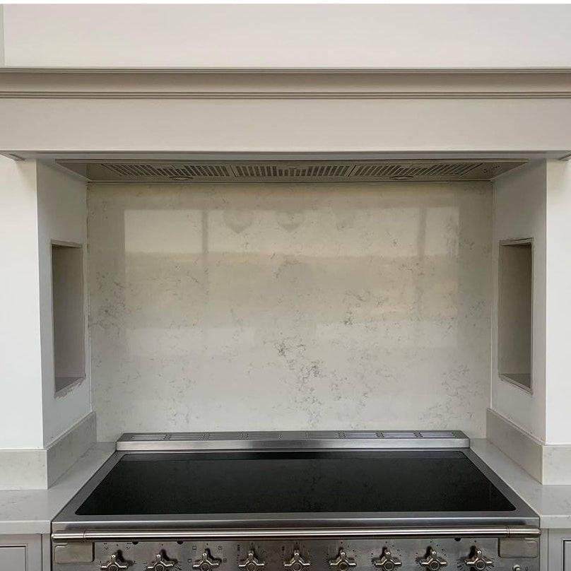 Luxair 120cm stainless steel canopy cooker hood integrated into a white chimney breast above a professional range cooker and marble backsplash.
