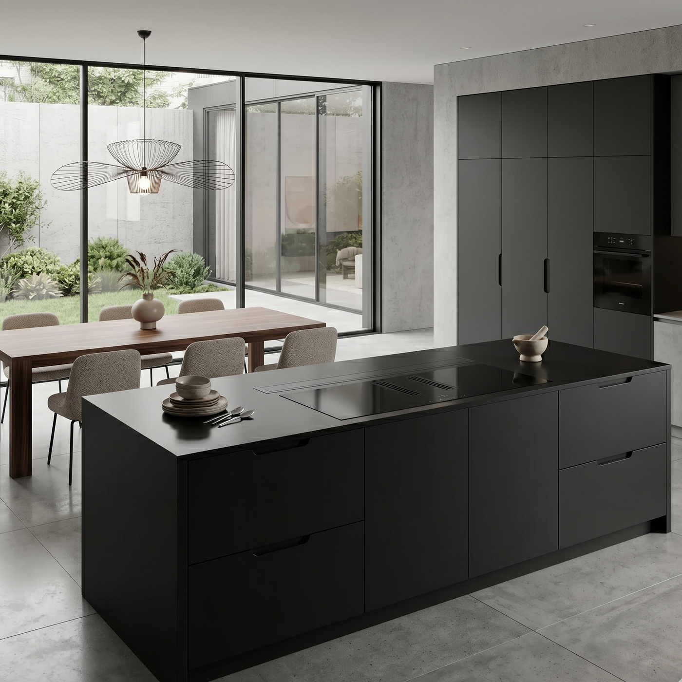 A sleek, 180cm black downdraft cooker hood is fully retracted and flush with the countertop, sitting parallel to the hob. In a modern, minimalist  kitchen featuring a dark grey graphite island with a built-in induction hob.