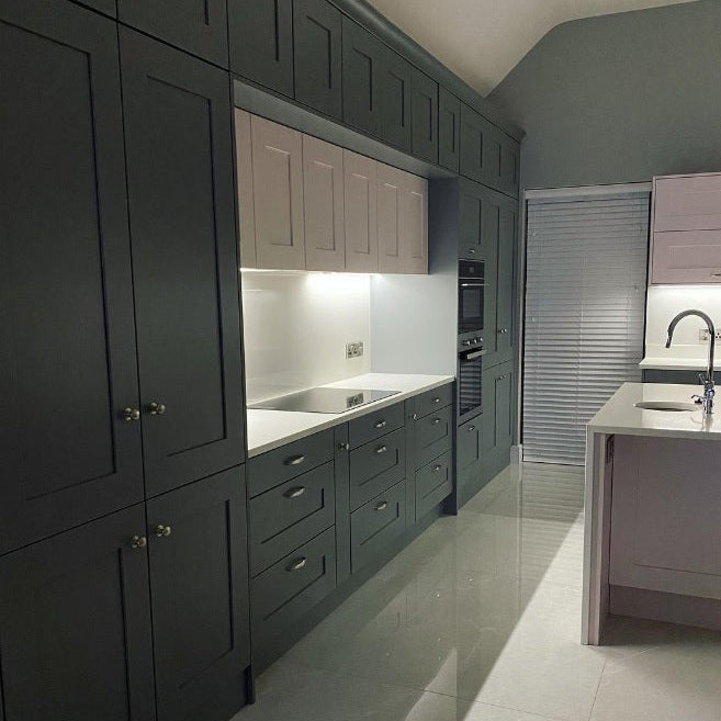 Modern dark grey and blush pink kitchen featuring a hidden 54cm built-in canopy cooker hood integrated into Shaker-style cabinets over a white quartz countertop.