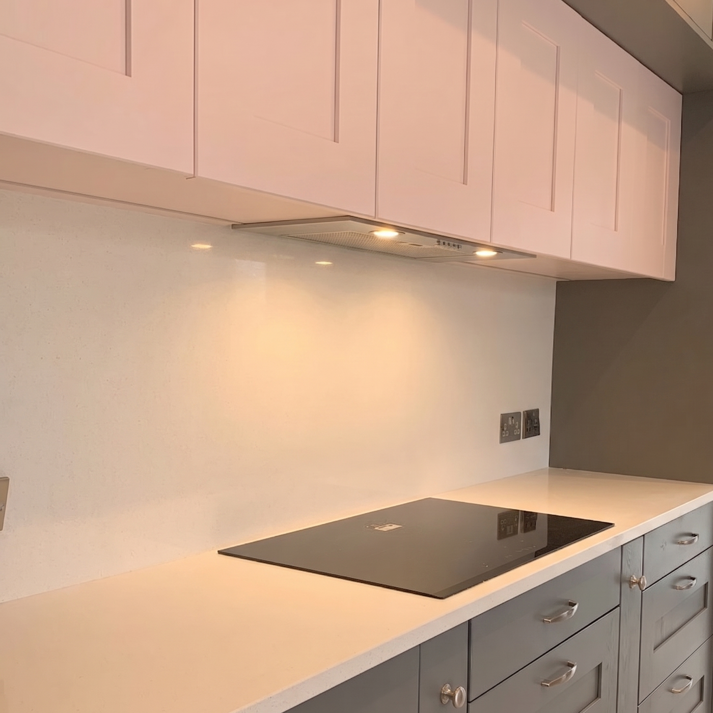 Modern dark grey and blush pink kitchen featuring a 54cm built-in canopy cooker hood integrated into Shaker-style cabinets over a white quartz countertop.