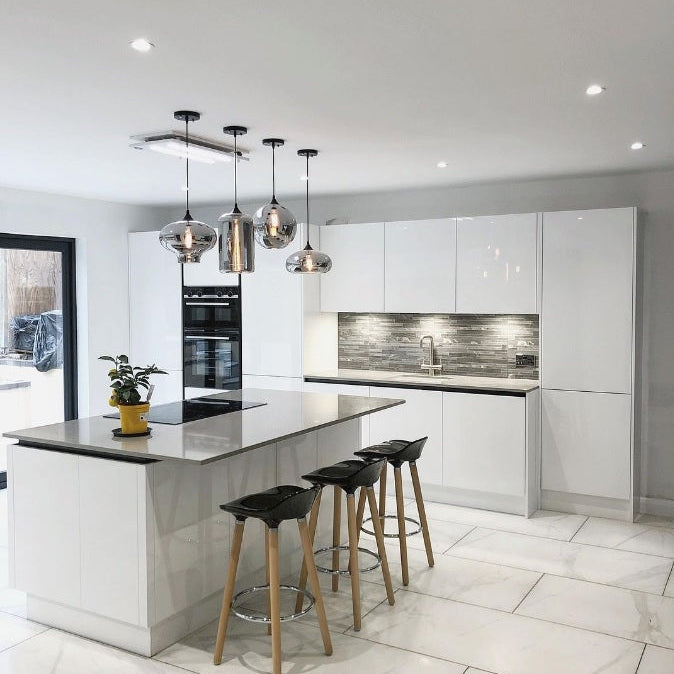 Luxair 800mm white slimline ceiling cooker hood installed over a modern kitchen island with white gloss cabinets and glass pendant lights.