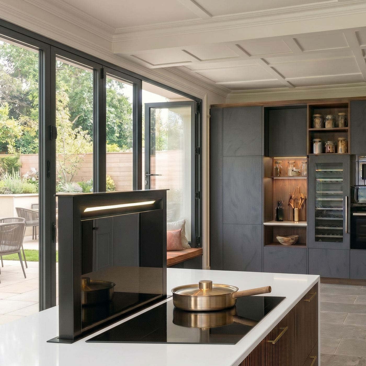 Modern luxury kitchen island with integrated induction hob and black downdraft extractor, featuring white quartz worktops, dark fluted wood cabinetry, and anthracite bifold doors.