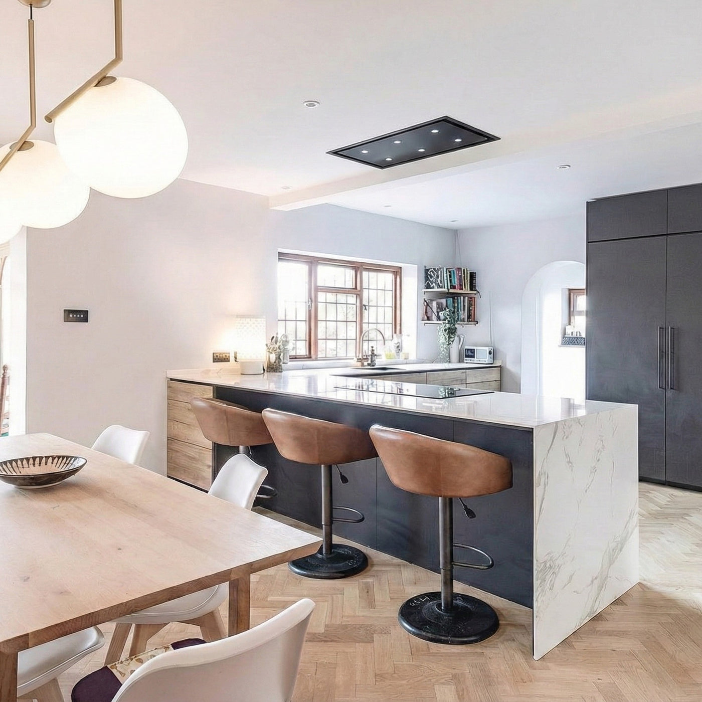 90cm x 50cm Anzi Black Cooker Hood Installed In A Modern kitchen with marble island, wooden dining table, and bar stools.