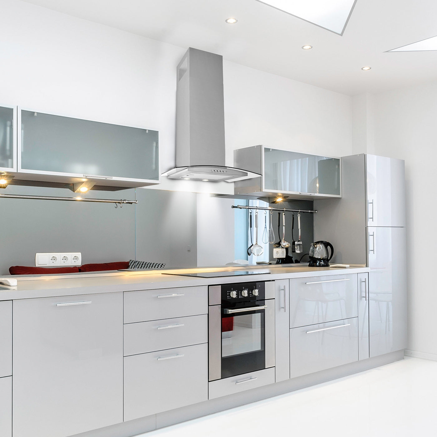 Stainless Steel Artis curved cooker hood installed within a modern grey kitchen with stainless backsplash