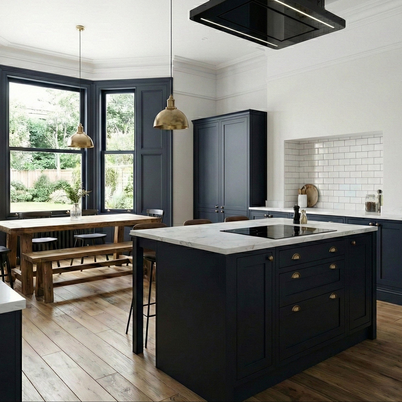 90cm Orion Recirculating Ceiling Cooker Hood Installed Within a Shaker Style Kitchen With Black Island, White Marble Countertops, and Wooden Dining Area.