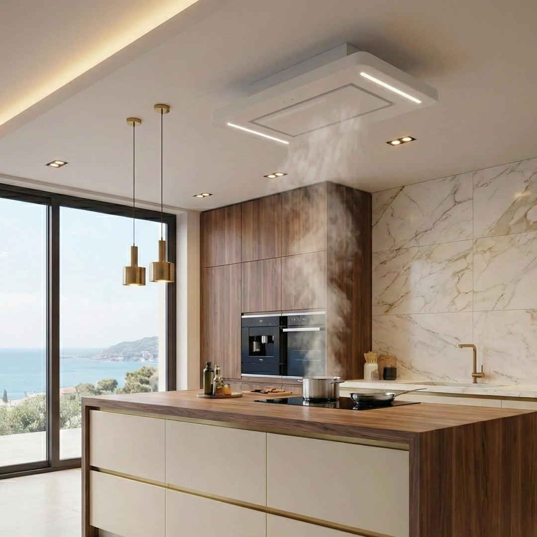 90cm Orion Recirculating Ceiling Cooker Hood Extracting In a Modern Kitchen With Marble Walls, Wooden Cabinets, and a Coastal View.