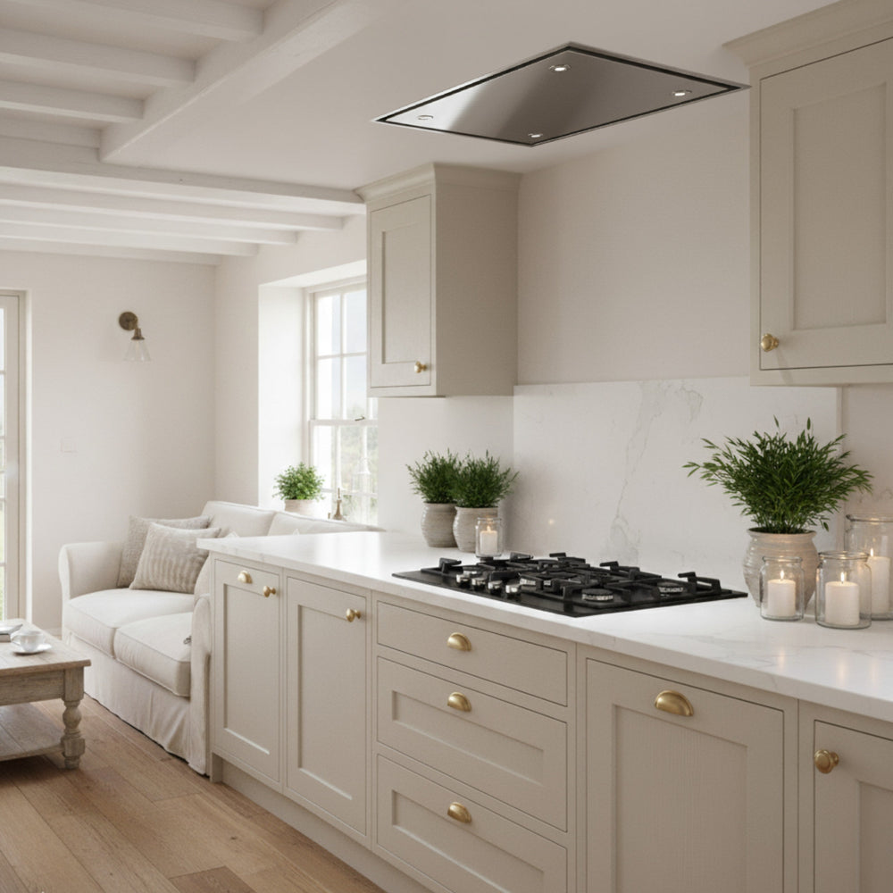 Stainless Steel Skyline Cooker Hood In a Modern kitchen With Beige Cabinets, Marble Countertop, And a View Into a Living Room.