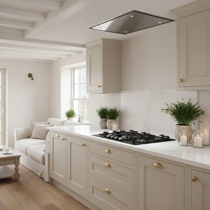 Stainless Steel Skyline Cooker Hood In a Modern kitchen With Beige Cabinets, Marble Countertop, And a View Into a Living Room.