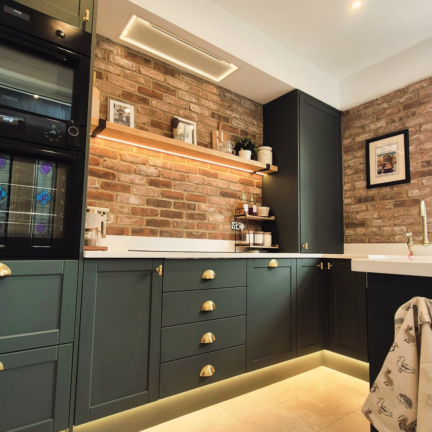 90cm x 30cm White Soffitto Ceiling Cooker Hood In a Modern Kitchen With Green Cabinets, Brick Wall, and Wooden Shelf, LED Lighting Surround