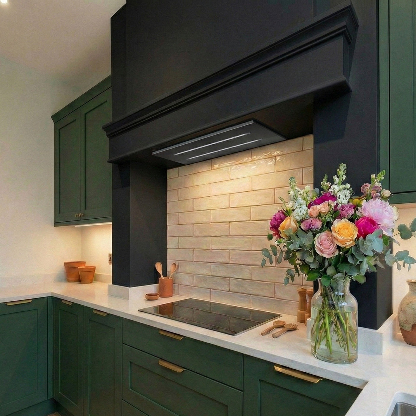 Modern kitchen featuring forest green shaker cabinets with gold handles, a black chimney breast extractor, and a black 80cm small slimline ceiling cooker hood over an induction hob