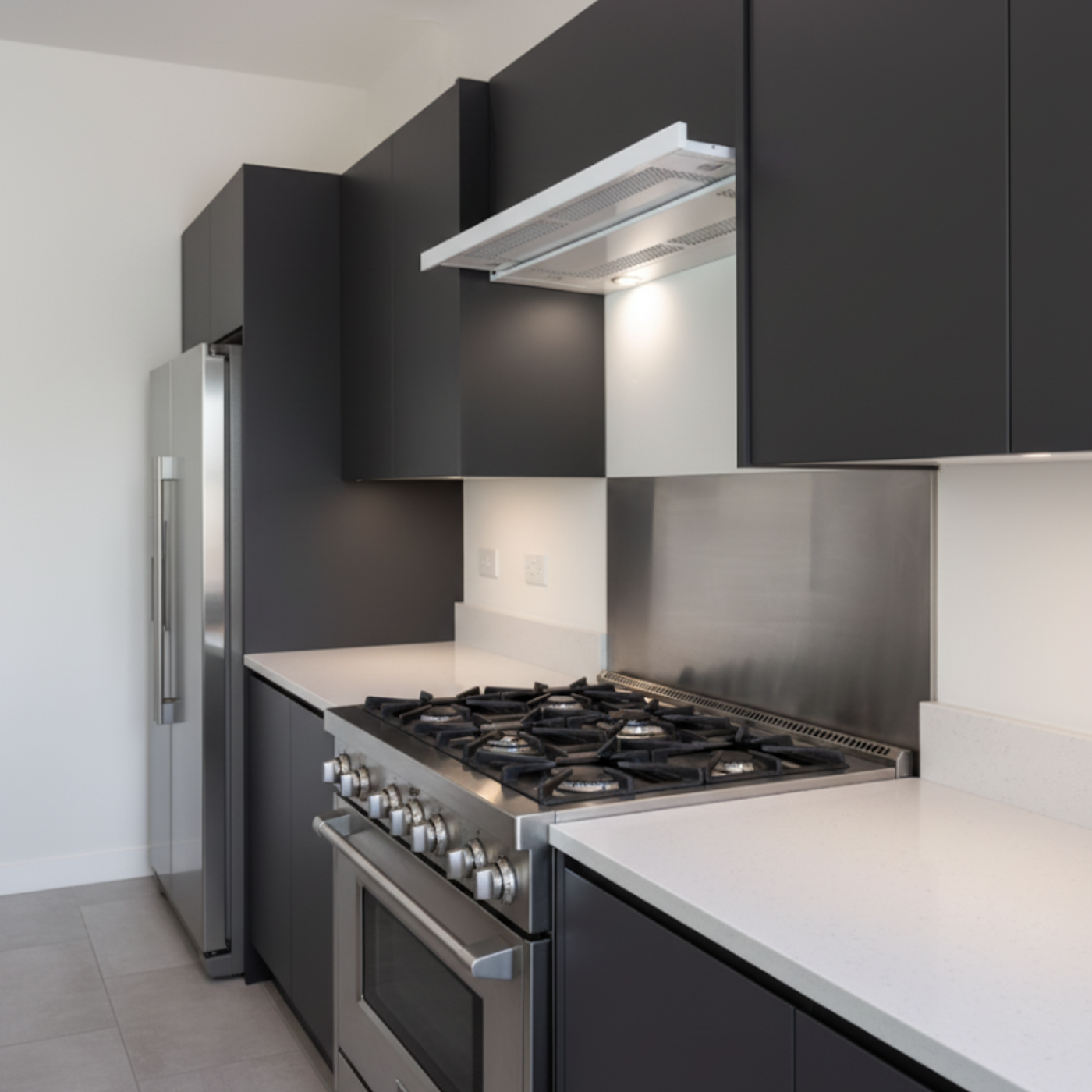 Telescopic Cooker Hood White Installed In A Sleek Black Kitchen With Stainless Steel Splashback
